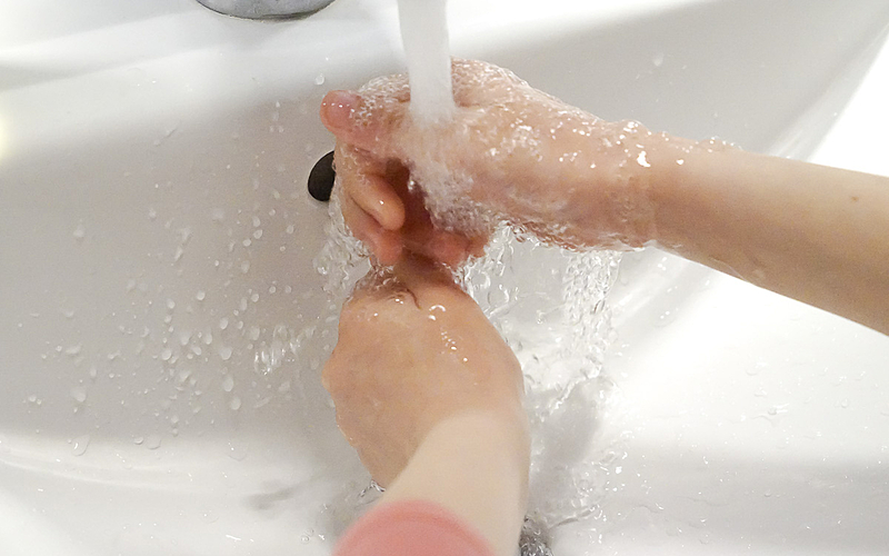 Enfant se lavant les mains avec du savon dans une salle de bains sous le robinet 