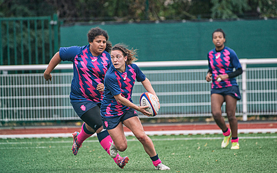 Une joueuse du Stade Français avec le ballon en pleine action.