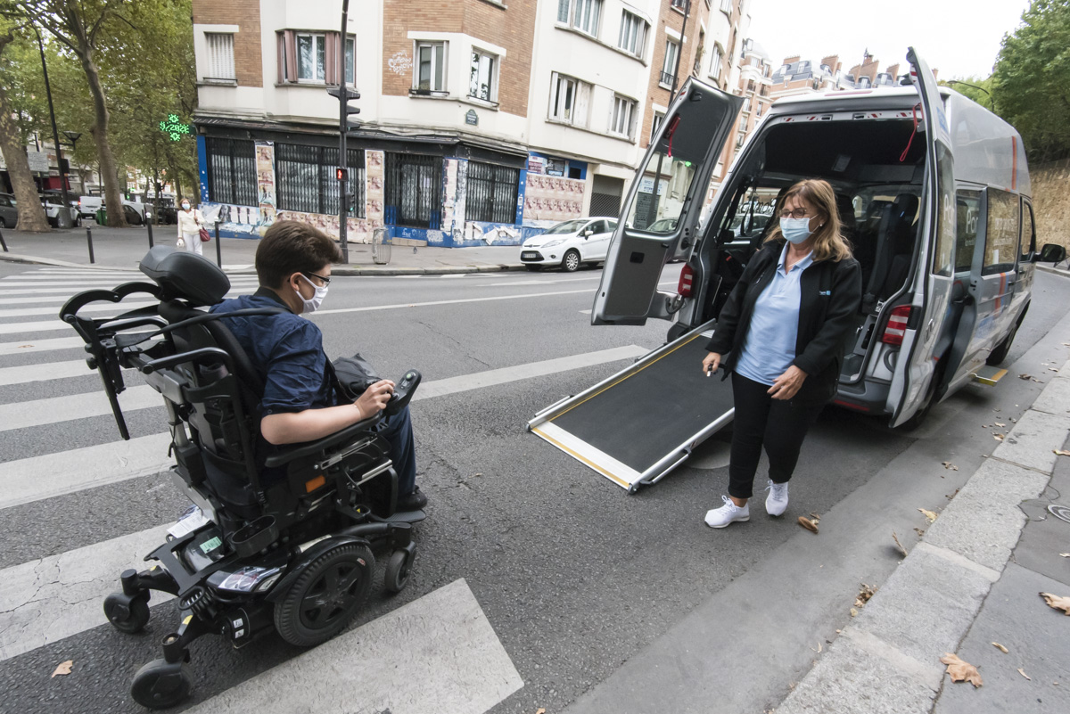 Une personne en fauteuil roulant entre dans le véhicule PAM.