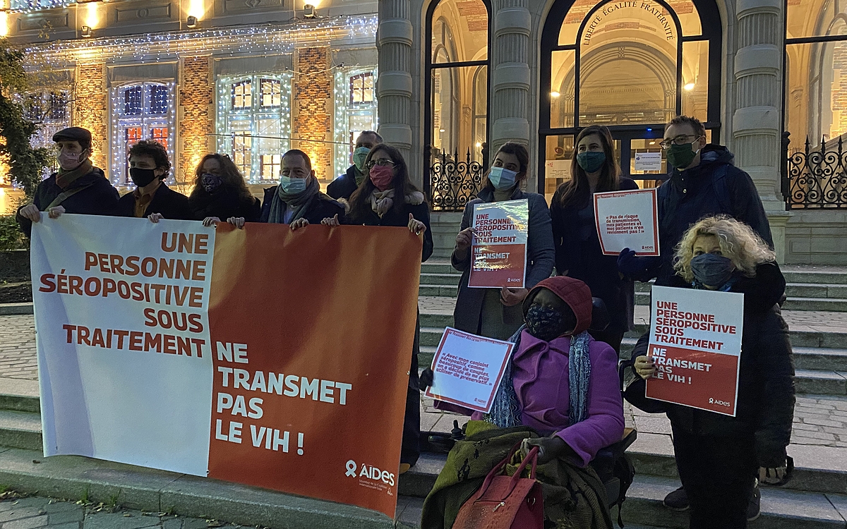 Une dizaine d'élu·es de la majorité municipale, devant la Mairie, tiennent une banderole de l'association Aides où est écrit "Une personne séropositive sous traitement ne transmet pas le VIH !"