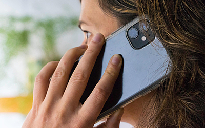 Une personne tient un téléphone à la main posé sur son oreille.