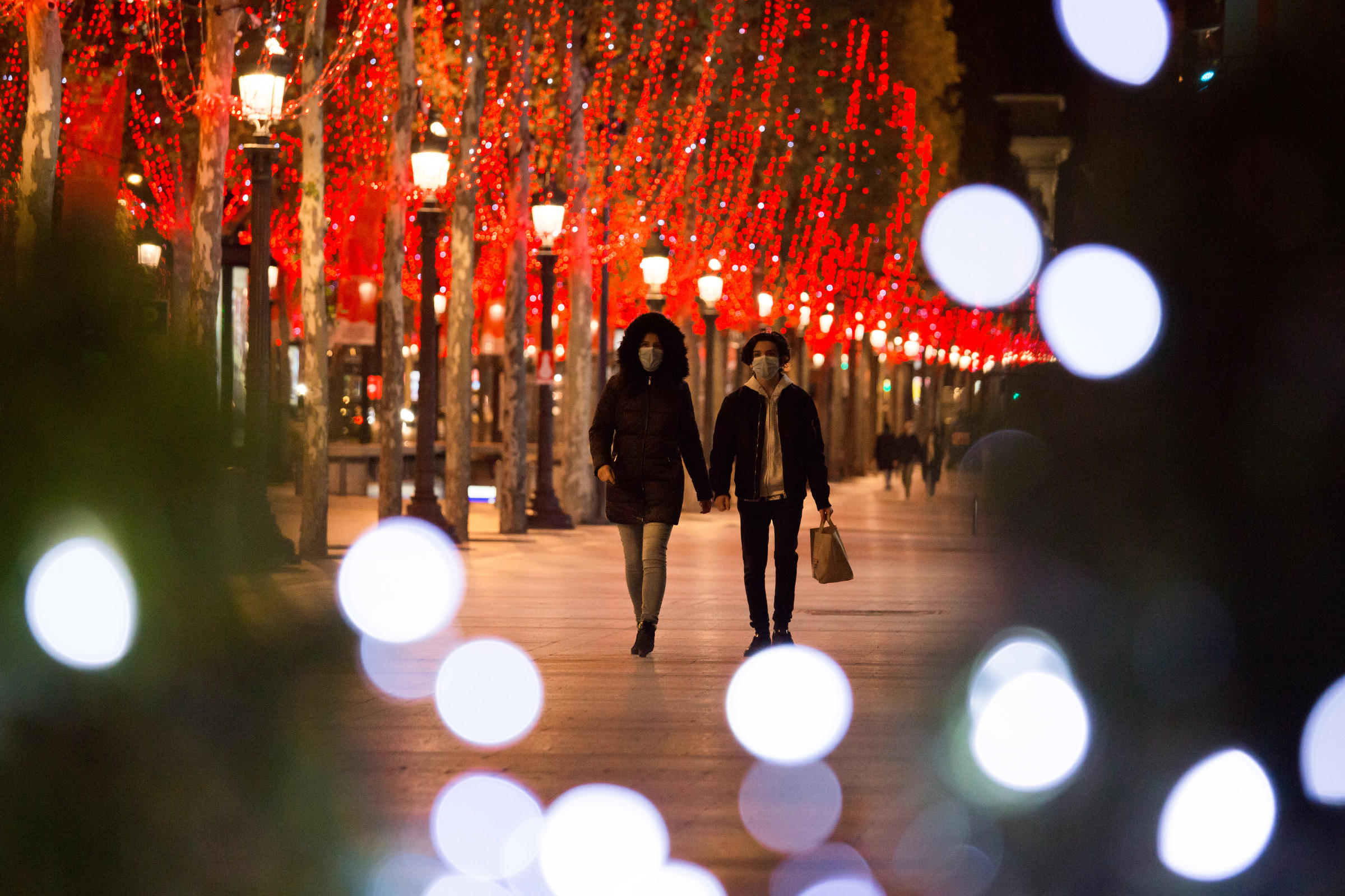 Un couple se balade masqué sur les Champs Elysées.