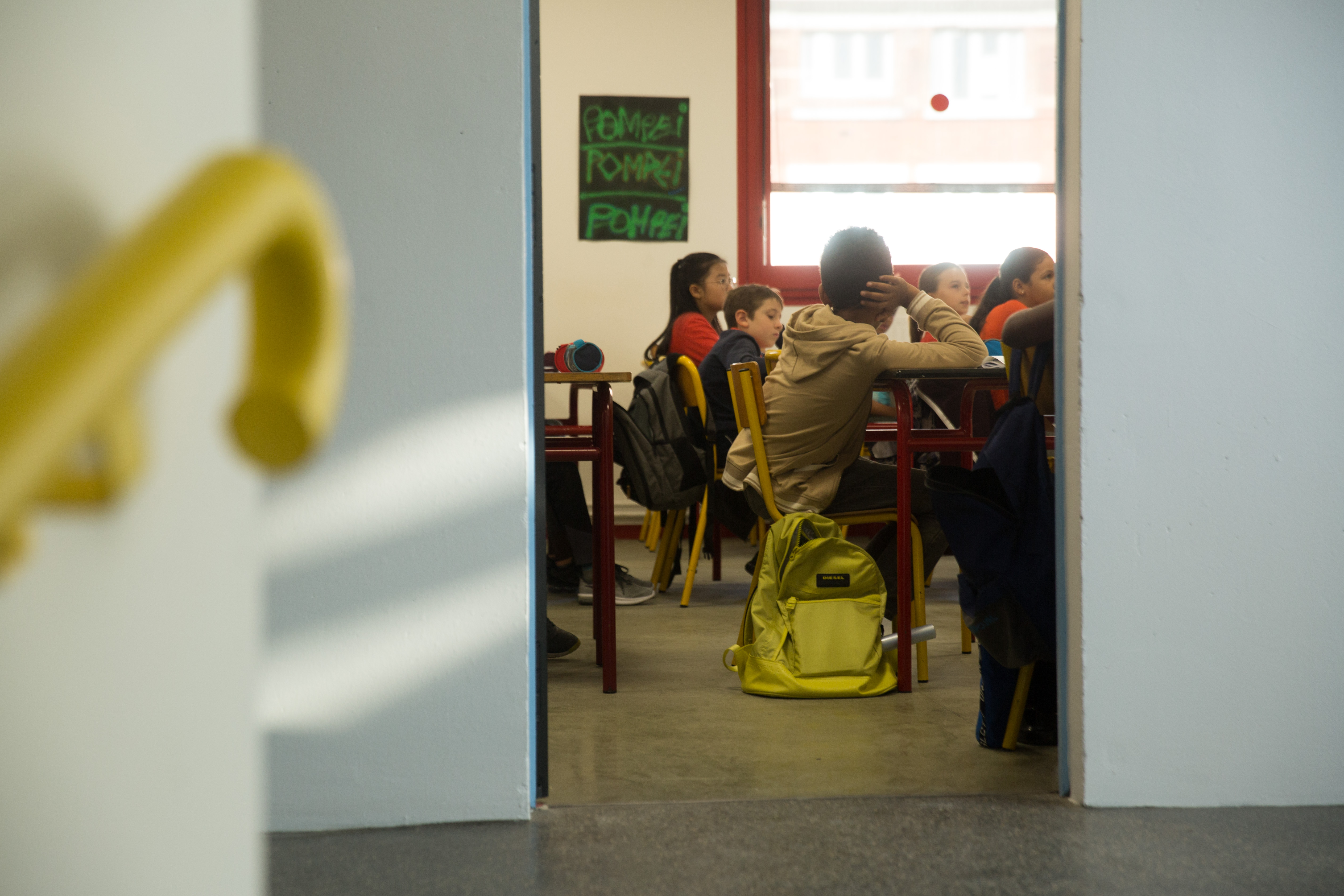 Classe de collège vue depuis le haut d'un escalier via une porte ouverte