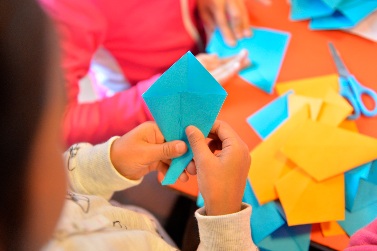 Une enfant fabrique une origami.