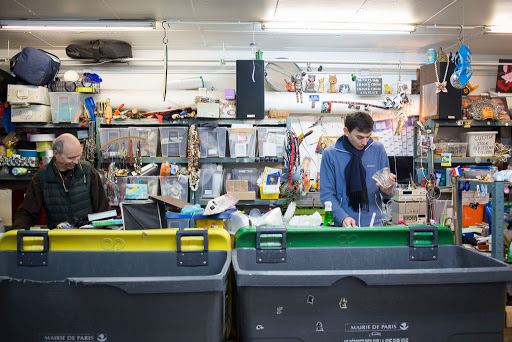 Deux hommes dans un atelier en train de trier et réparer des objets et équipements