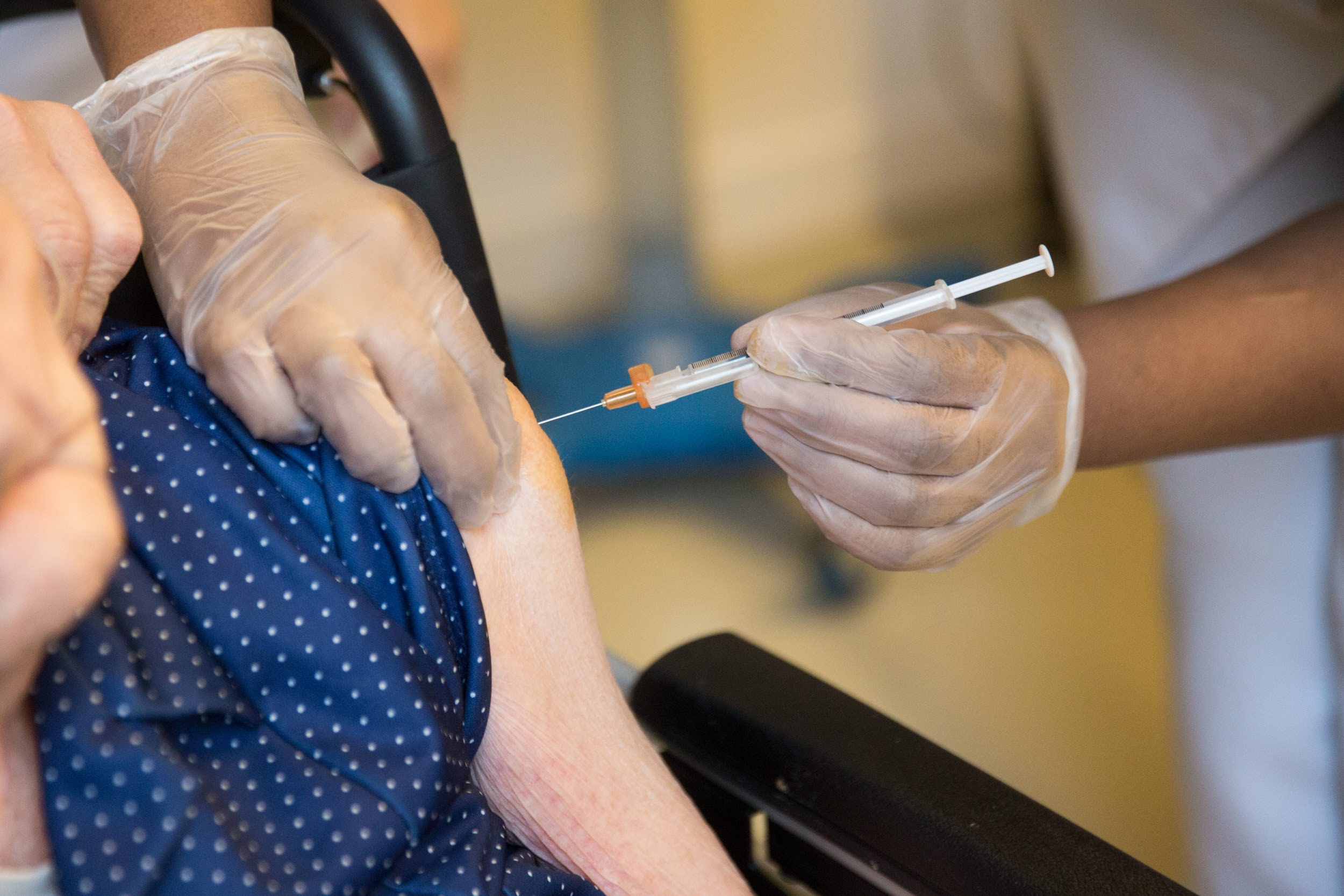 Personne âgée se faisant vaccinée contre le covid-19, gros plan sur le bras se faisant piqué avec la seringue et l'aiguille