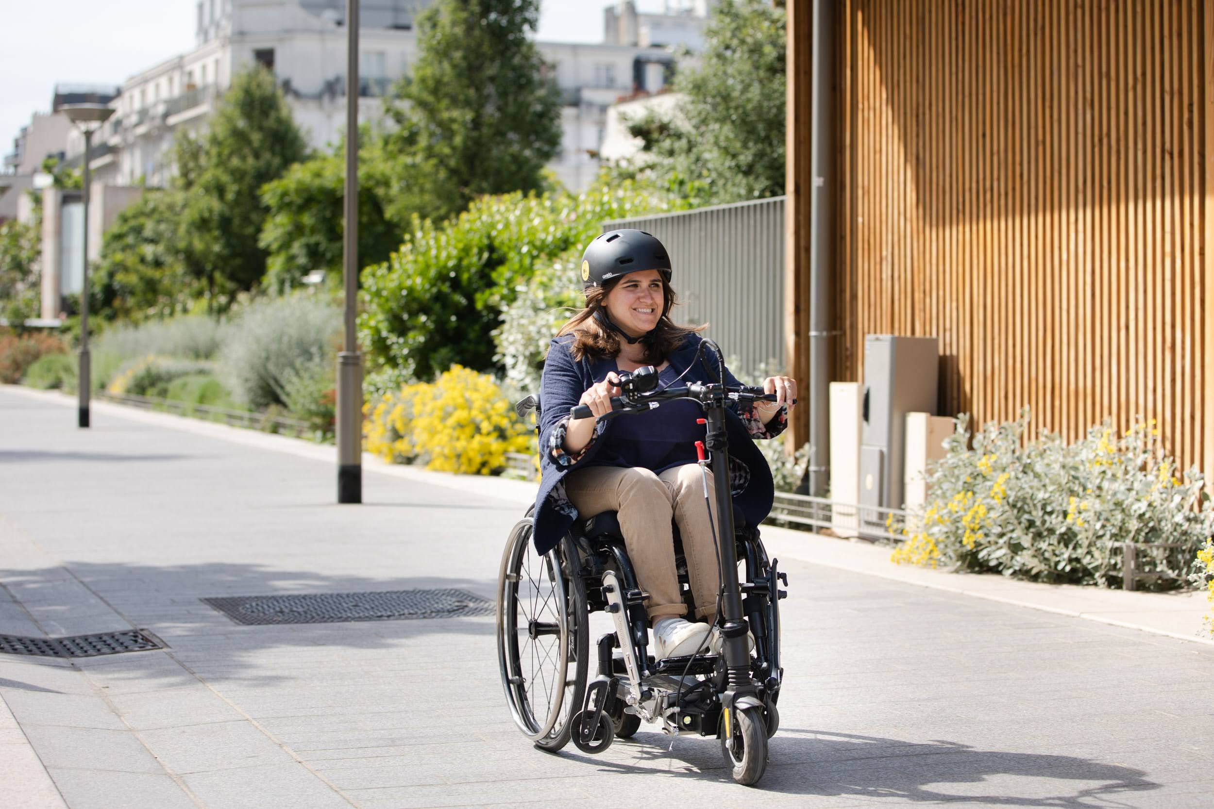 Une personne dans un fauteuil roulant utilise un système motorisé avec un guidon de trottinette électrique