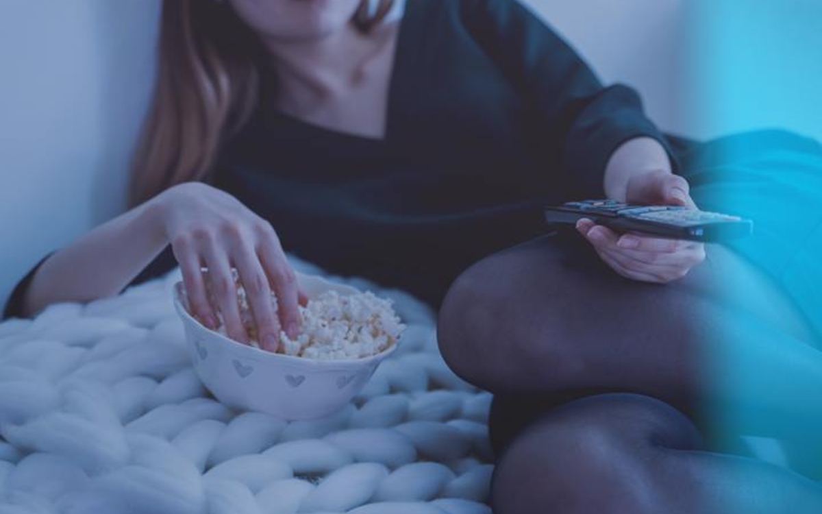 Femme allongée avec télécommande dans la main
