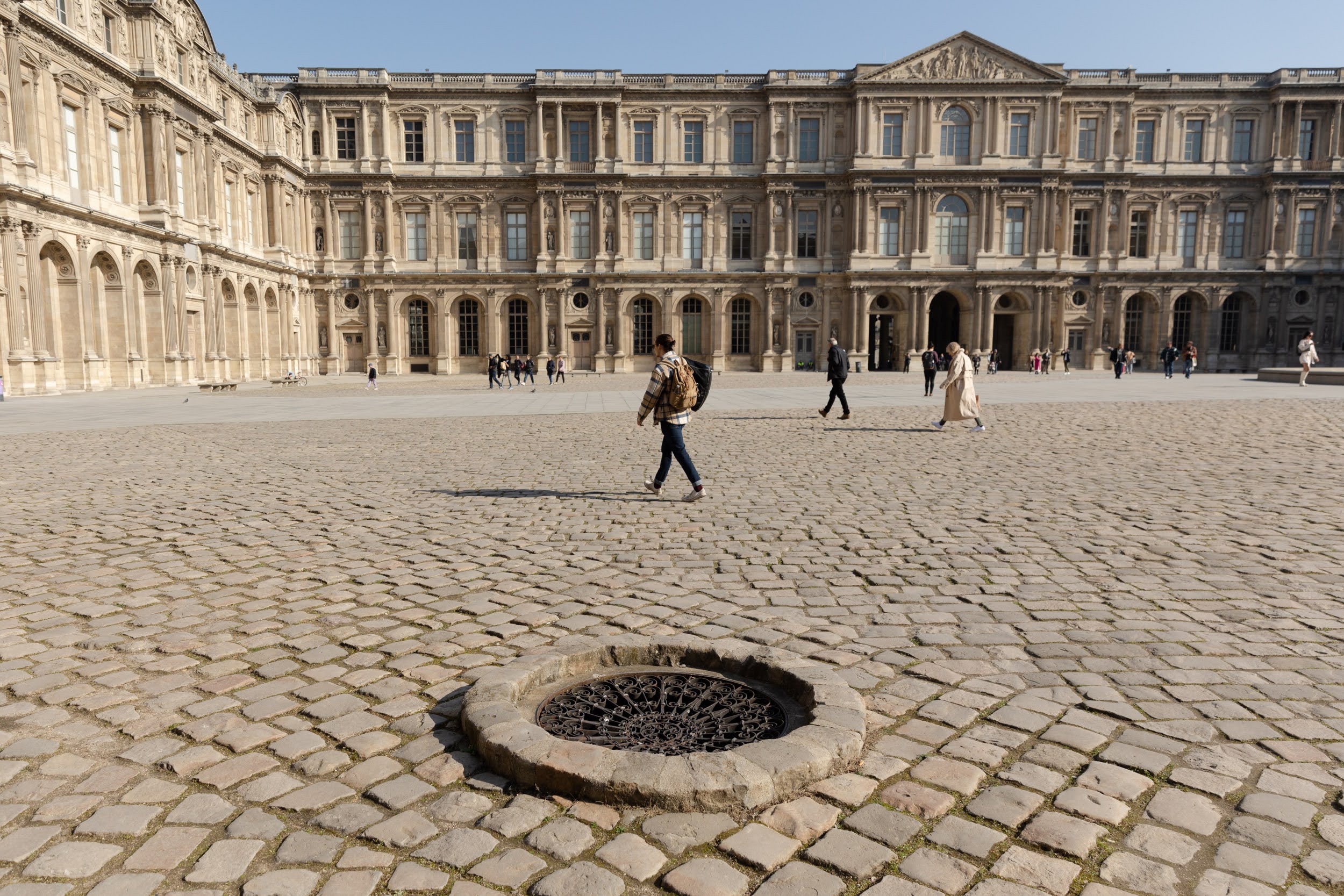 Cour carrée du Louvre avec des passants au loin.