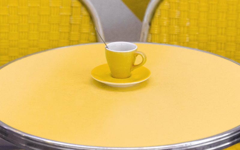 Deux chaises jaunes et une table jaune avec une tasse jaune dans un café rue de la gaité