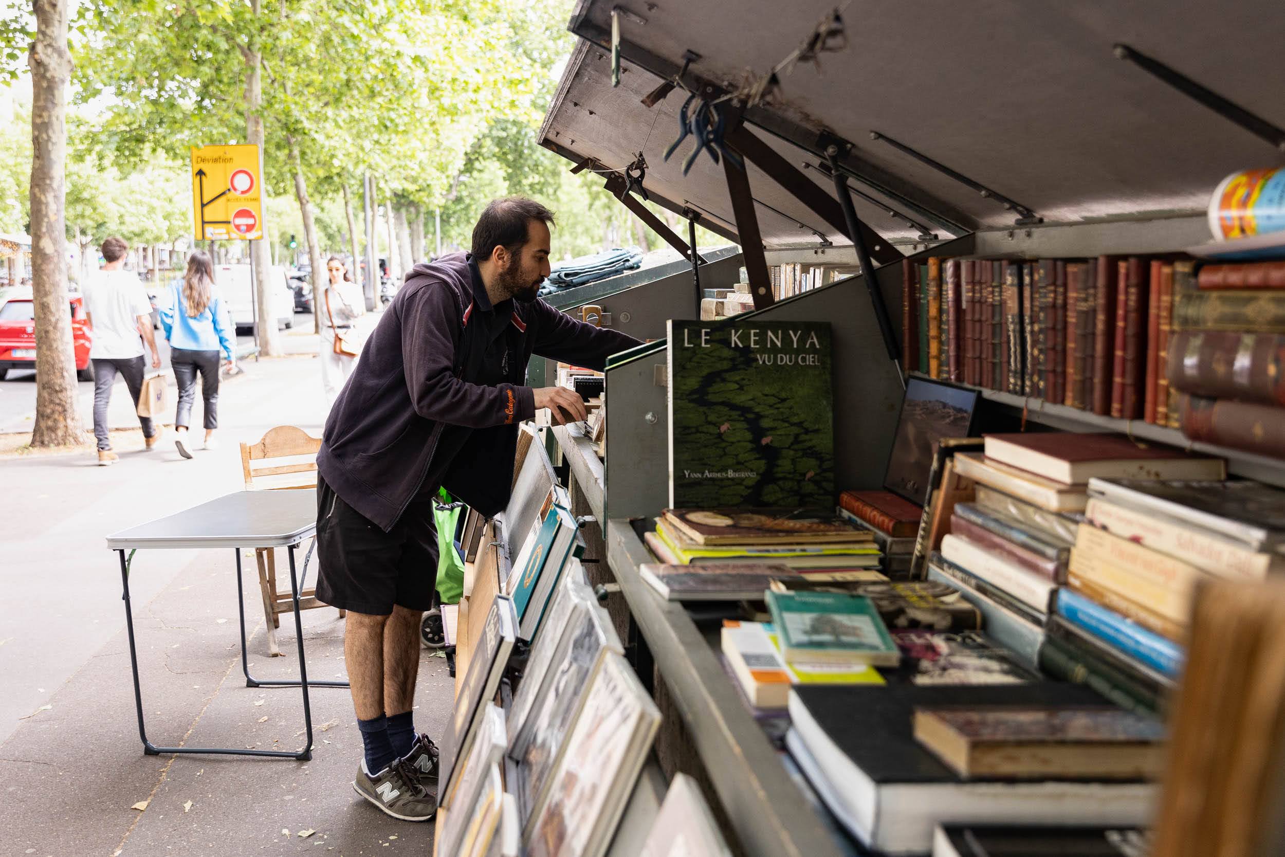 Client devant les boites de Rachid BOUANOU bouquiniste installé en mai 22, 48 quai de l’Hôtel de Ville