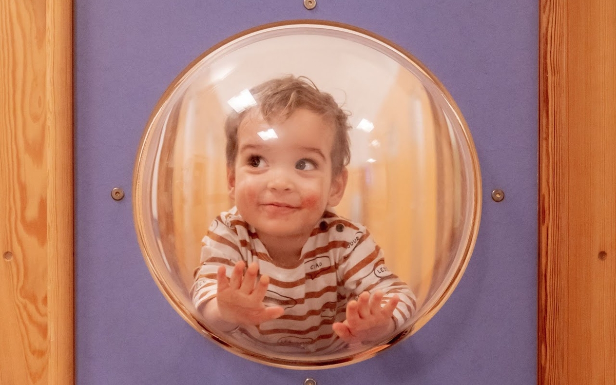 Jeune enfant derrière la vitre d'une porte dans une crèche