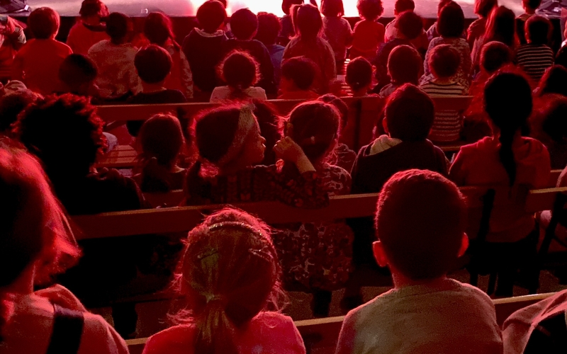 Des enfants patientent sur les bancs du théâtre Mandapa