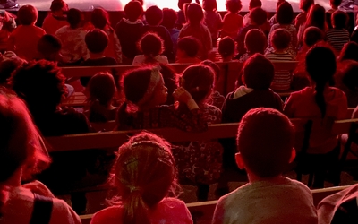 Des enfants patientent sur les bancs du théâtre Mandapa