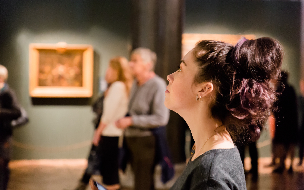 Jeune femme regardant un tableau lors d'une exposition artistique
