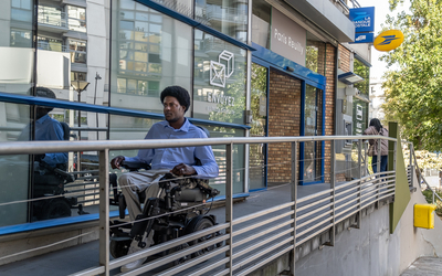 Personne en fauteuil roulant électrique devant une Poste