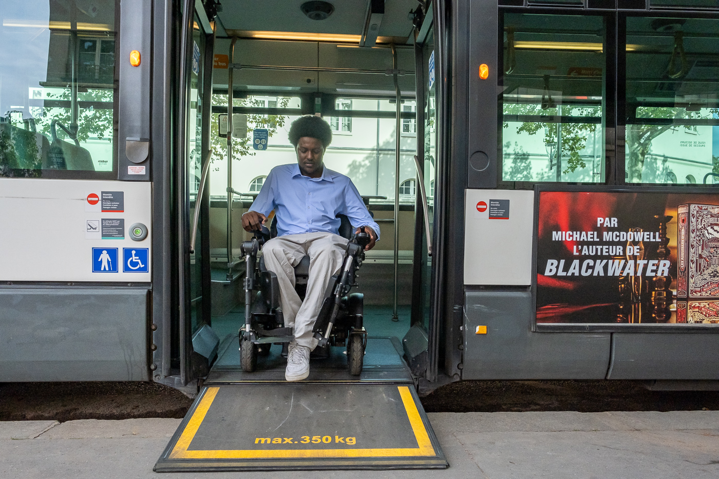  Personne en fauteuil roulant descendant d'un bus sur une rampe d'accès PMR