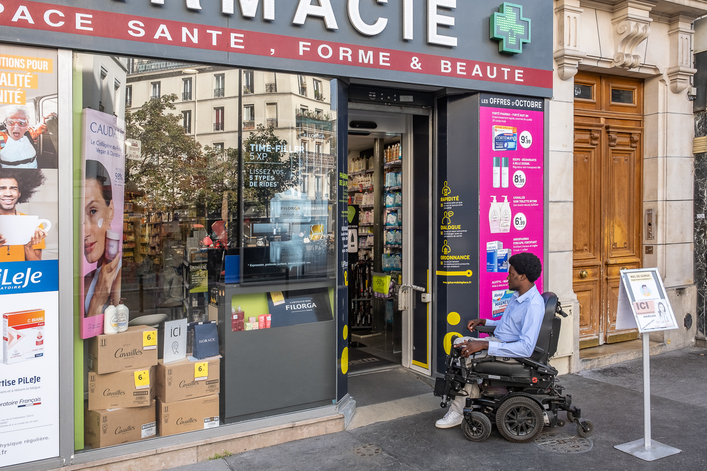 Souleyman Youssouf, habitant du 12e arrondissement, en fauteuil roulant électrique, chemine dans le QAA du 12e arrondissement, ici devant une pharmacie