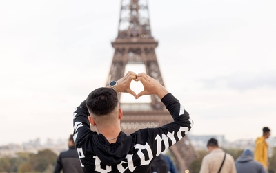 Un touriste forme un coeur avec les mains, devant la Tour Eiffel, sur l'esplanade du Trocadéro. 