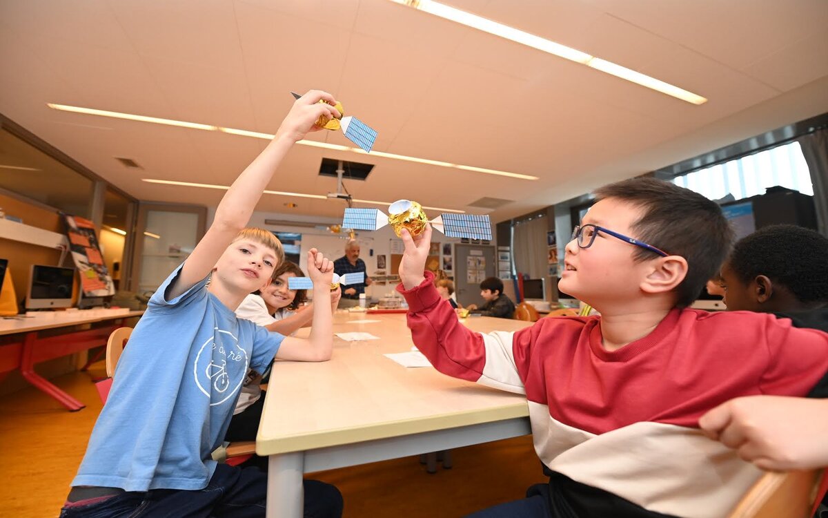 Des enfants montrent les mini satellites qu'ils ont fabriqué pendant un atelier d'"Espace dans ma ville"