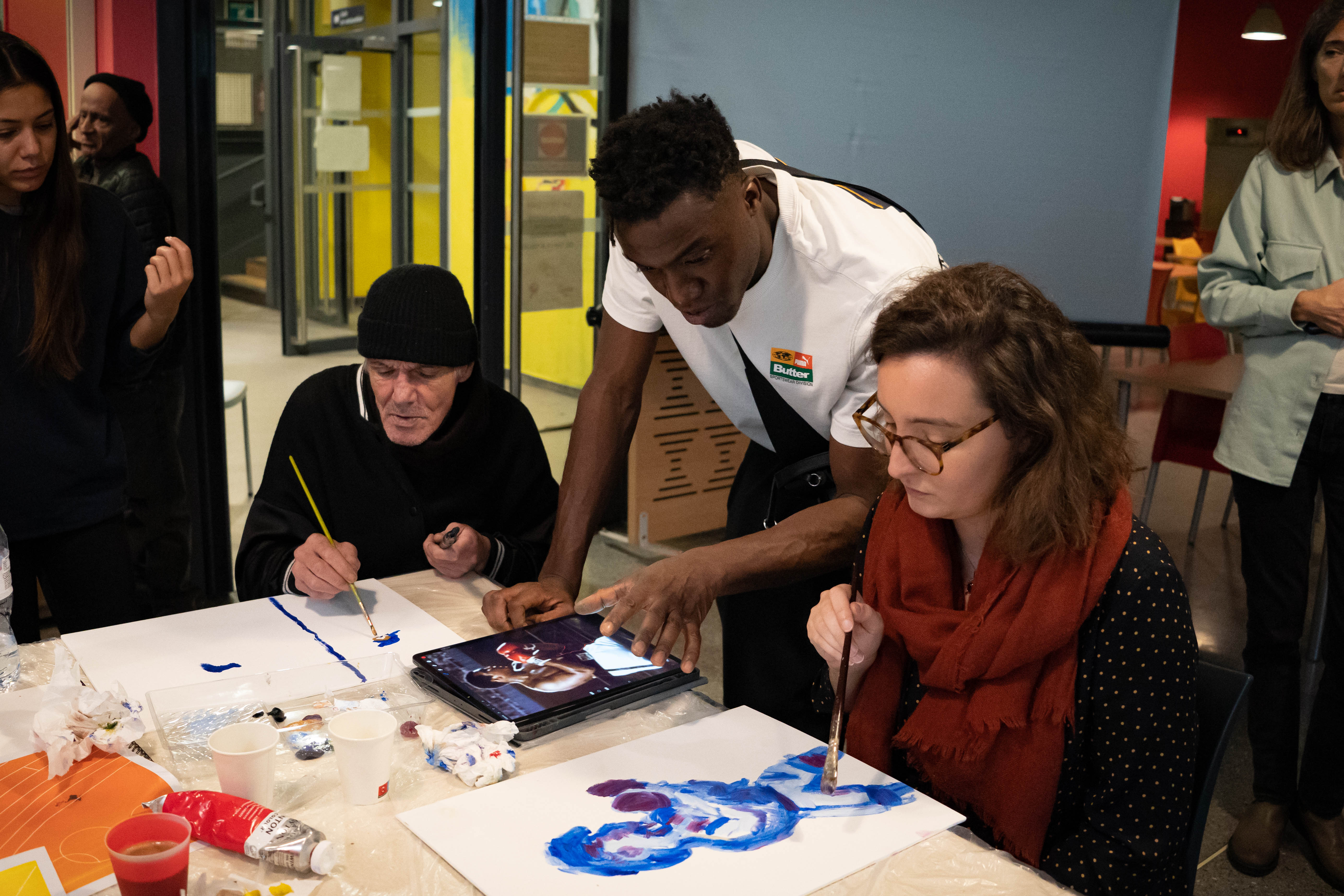 Luc Abalo montre une photo de boxeurs sur sa tablette à deux résidents