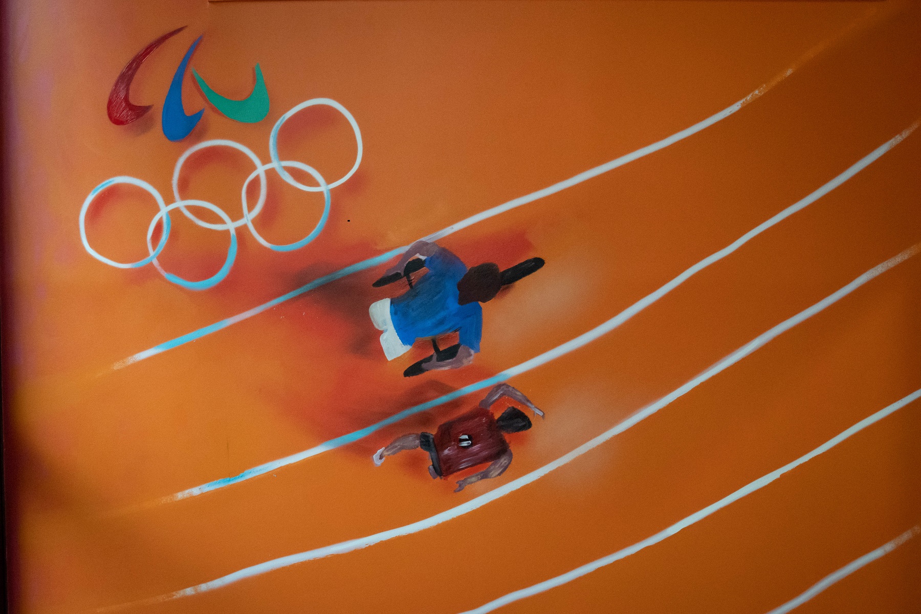 Fresque d'une piste d'athlétisme avec deux athlètes, dont l'un en fauteuil