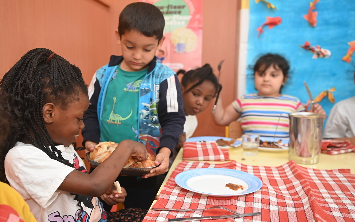 Un élève de maternelle sert ses camarades à la cantine