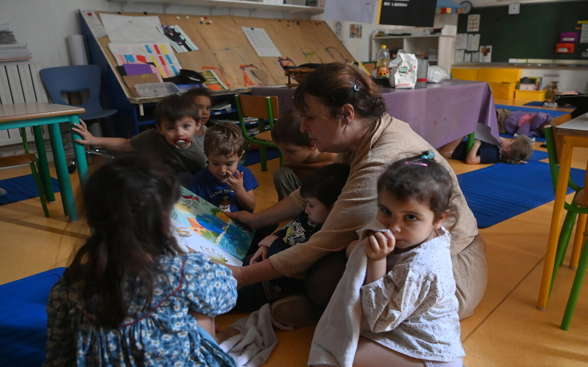 Une animatrice lit un livre avec des enfants de classe maternelle