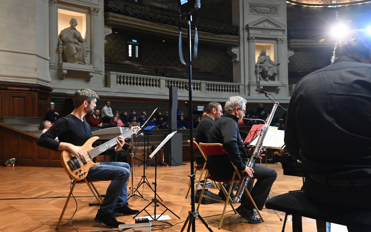 Sur l'estrade de l'amphithéâtre de la Sorbonne, des PVP jouent de la guitare, du basson et du piano