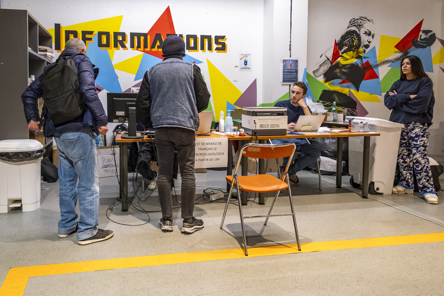 Différentes personnes autour d'une table dans le couloir du centre d'hébergement de la porte de Saint-Cloud