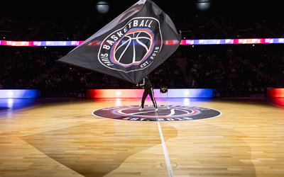 Un homme fait voler le drapeau du Paris Basketball lors de l'inauguration de l'Adidas Aréna, à la Chapelle. 