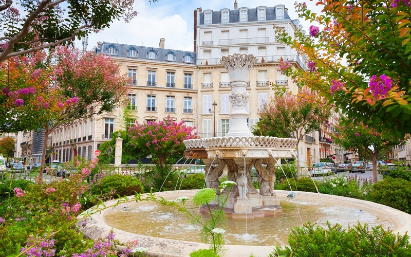 Photo de la fontaine de la place François 1er dans le 8e arrondissement, entourée d'arbres en fleurs