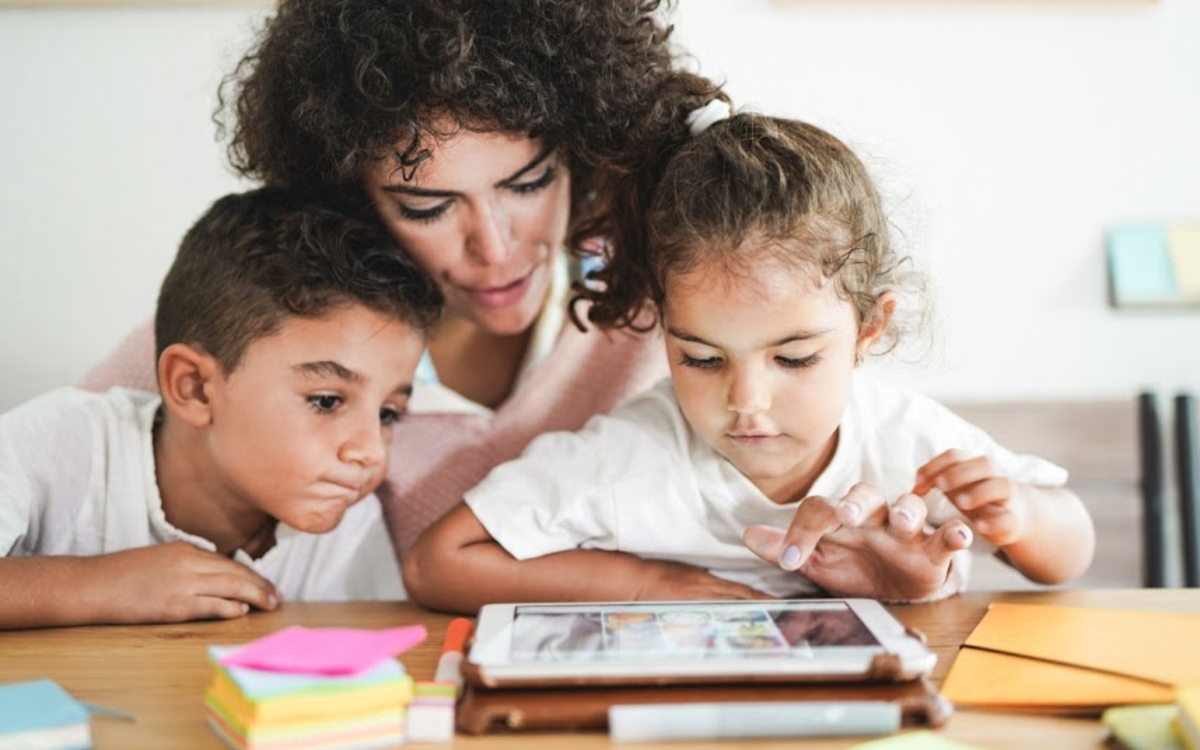 Maman avec ses deux enfants en  train de regarder une tablette