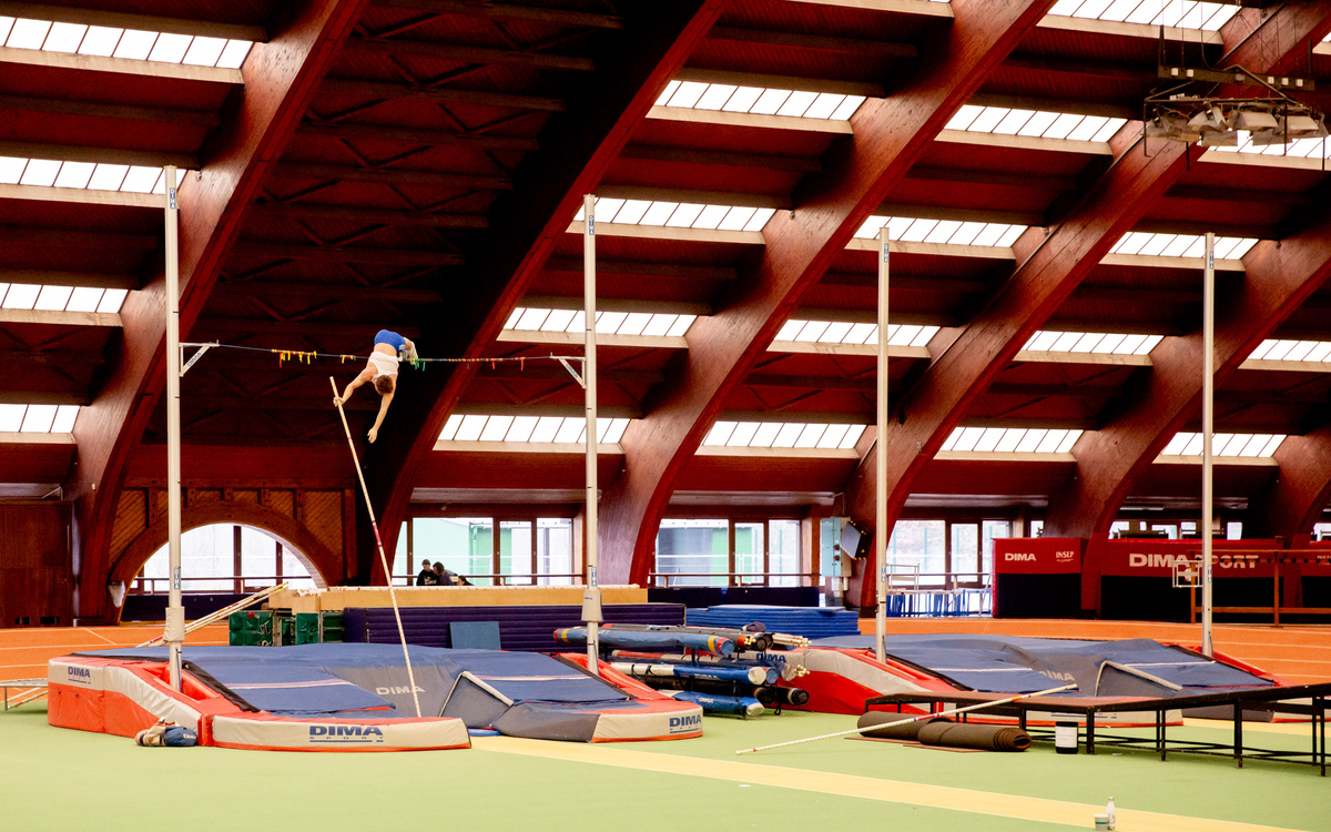 Un athlète effectue un saut en hauteur dans un gymnase.