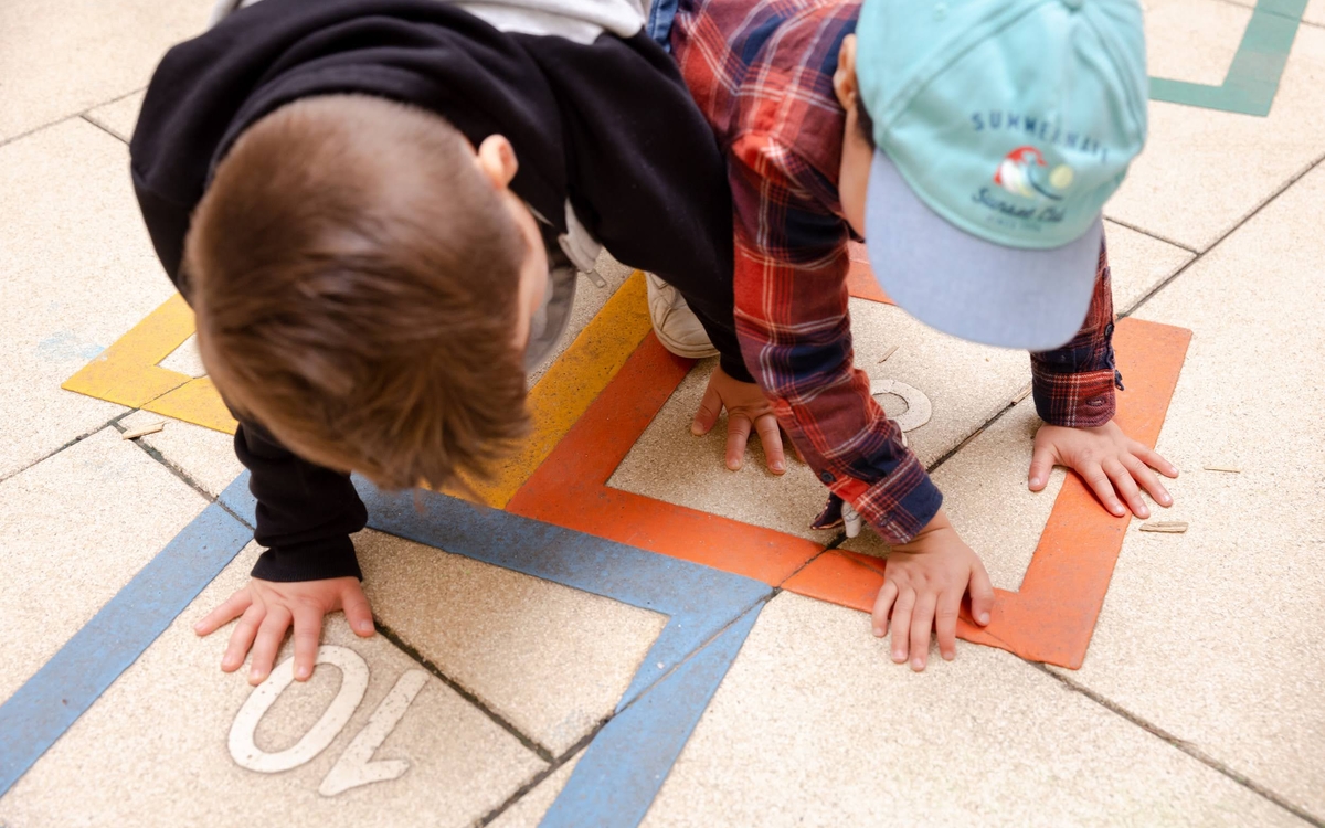 Deux enfants jouant avec des motifs imprimés sur le sol. 