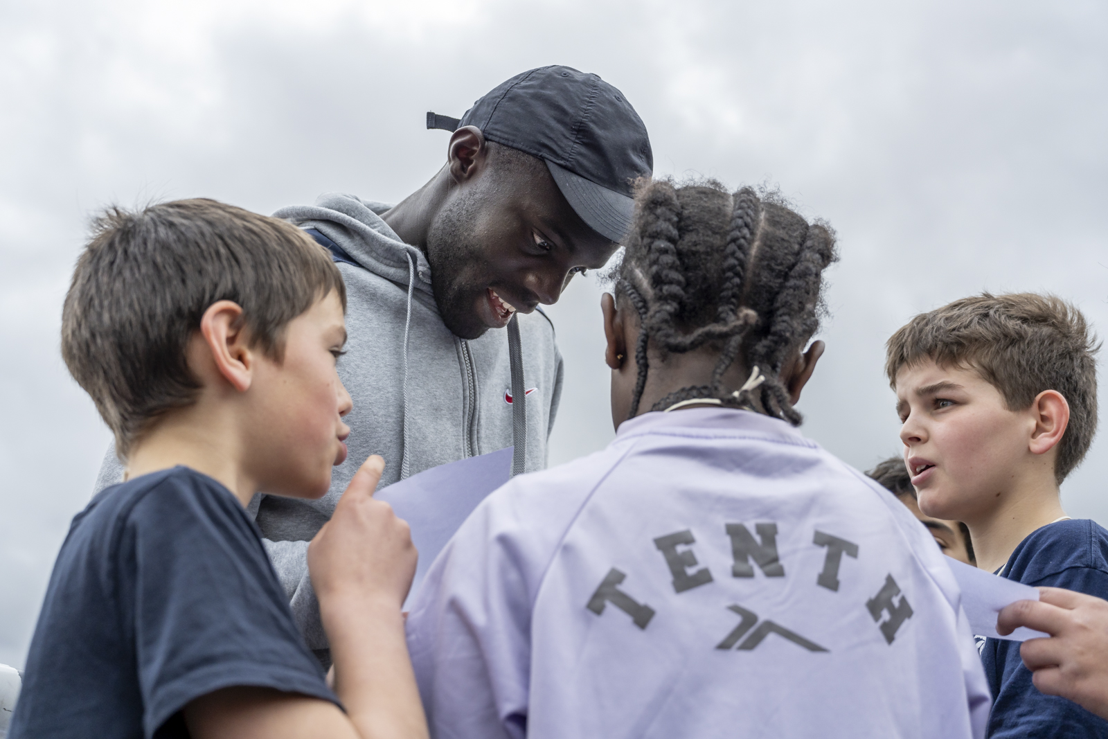 Charles-Antoine Kouakou is surrounded by three children and signing autographs.