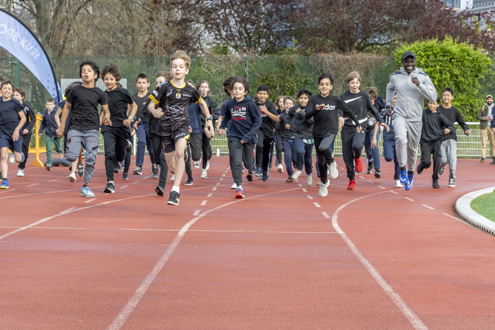 A crowd of CM2 children take to the track with Paralympic athlete Charles-Antoine Kouakou.