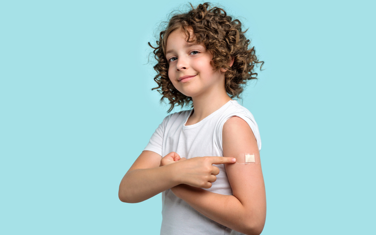 Un enfant montrant son pansement après s'être fait vacciné.
