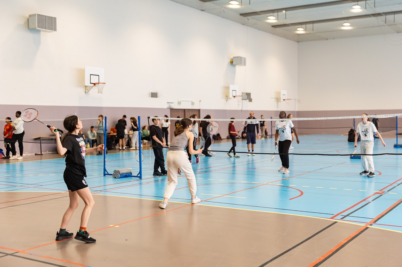 Des personnes jouent au badminton sur un terrain du gymnase Poissonniers