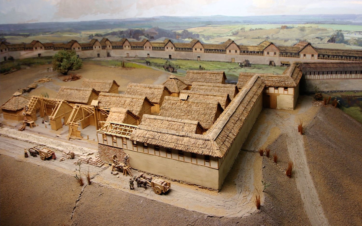 Une fortification en bois et torchis ceinture une large esplanade sur laquelle sont édifiées des habitations.