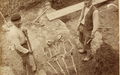 Deux hommes posant près de deux squelettes mis à jour lors des fouilles des Arènes, Paris,