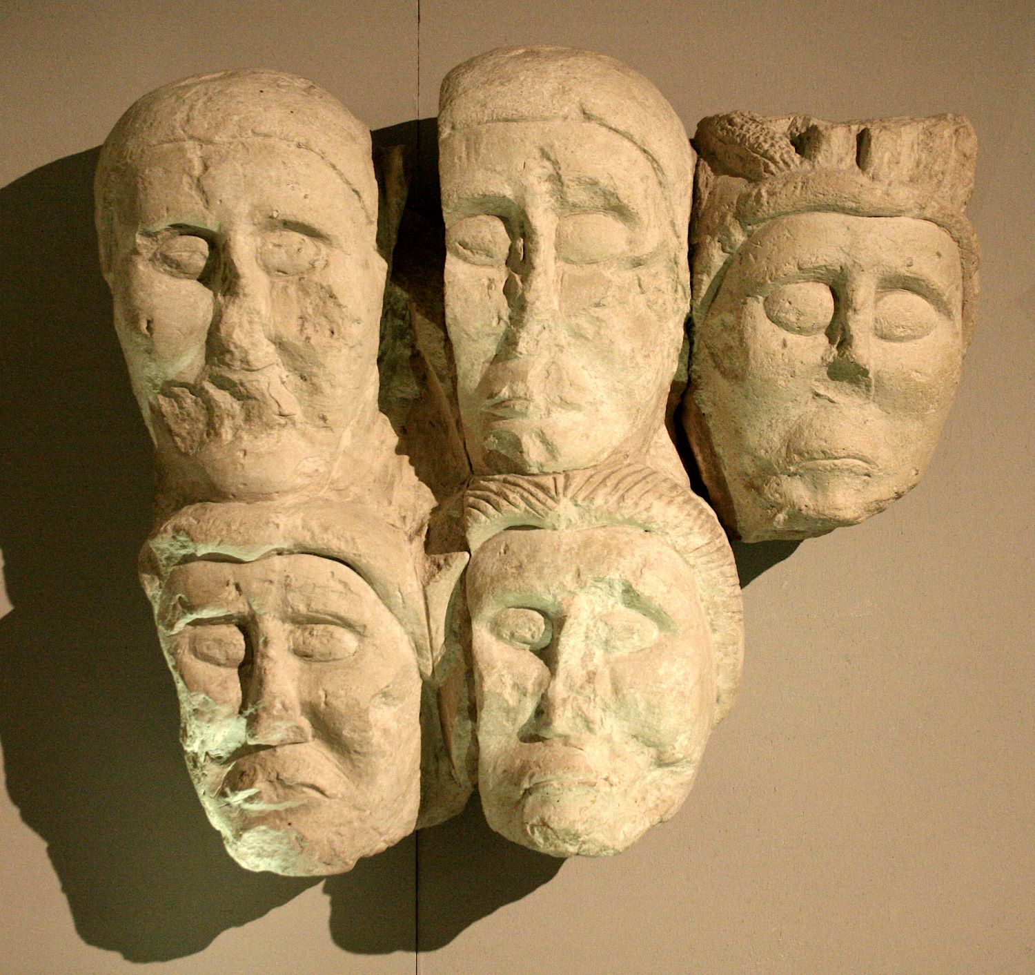 Cinq têtes sculptées arborant des cheveux courts et un visage glabre. 