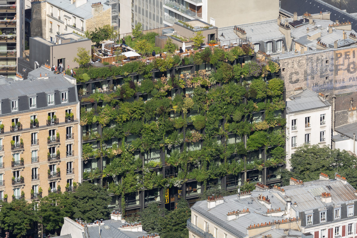 Vue aérienne sur un immeuble de 7 étages dont la façade est entièrement végétalisée. On ne distingue que les fenêtres et balcons de chaque habitation.