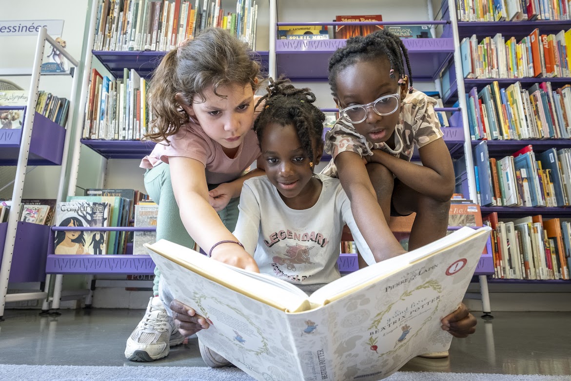 Trois enfants qui regardent un livre à la bibliothèque