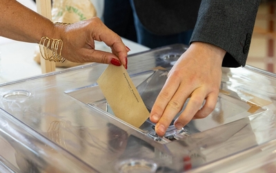 Photo d'une main glissant un bulletin de vote dans une urne