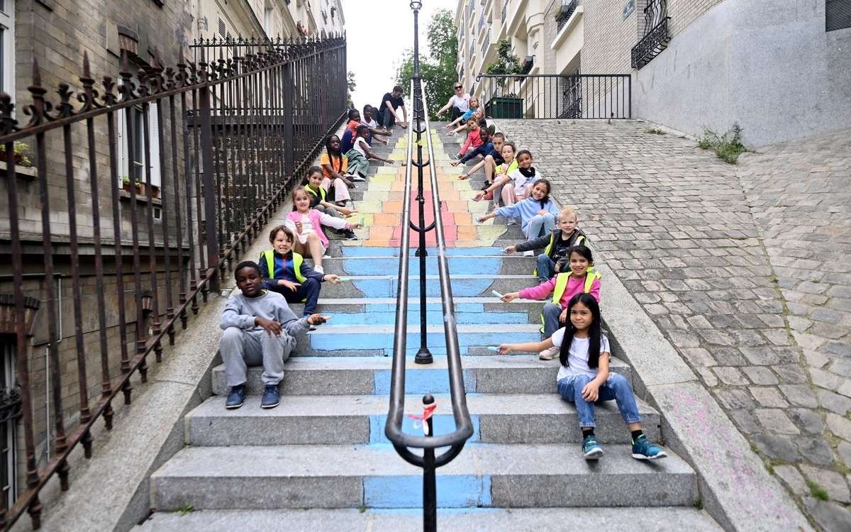 Des écoliers montrent la flamme olympique qu'ils ont dessinée sur les marches d'un escalier de Montrmatre