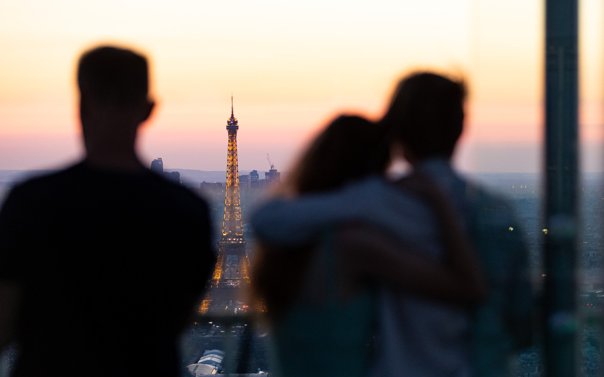 Des touristes regardent la tour Eiffel depuis la tour Montparnasse.