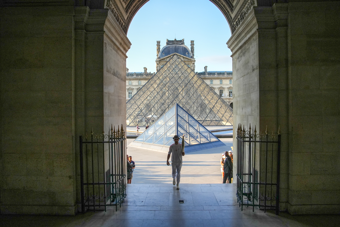 La flamme olympique illumine la pyramide du Louvre. 