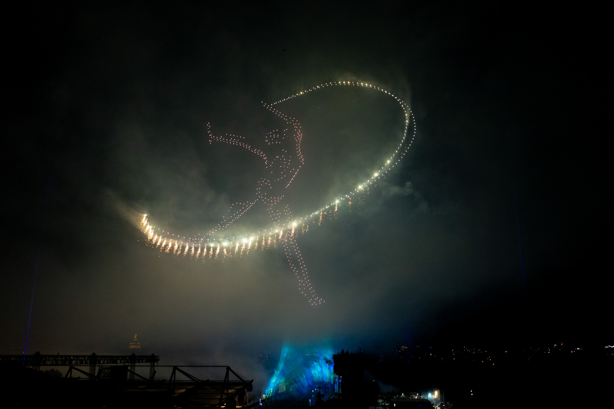 Des drones dessinent une gymnaste au ruban face à la tour Eiffel.