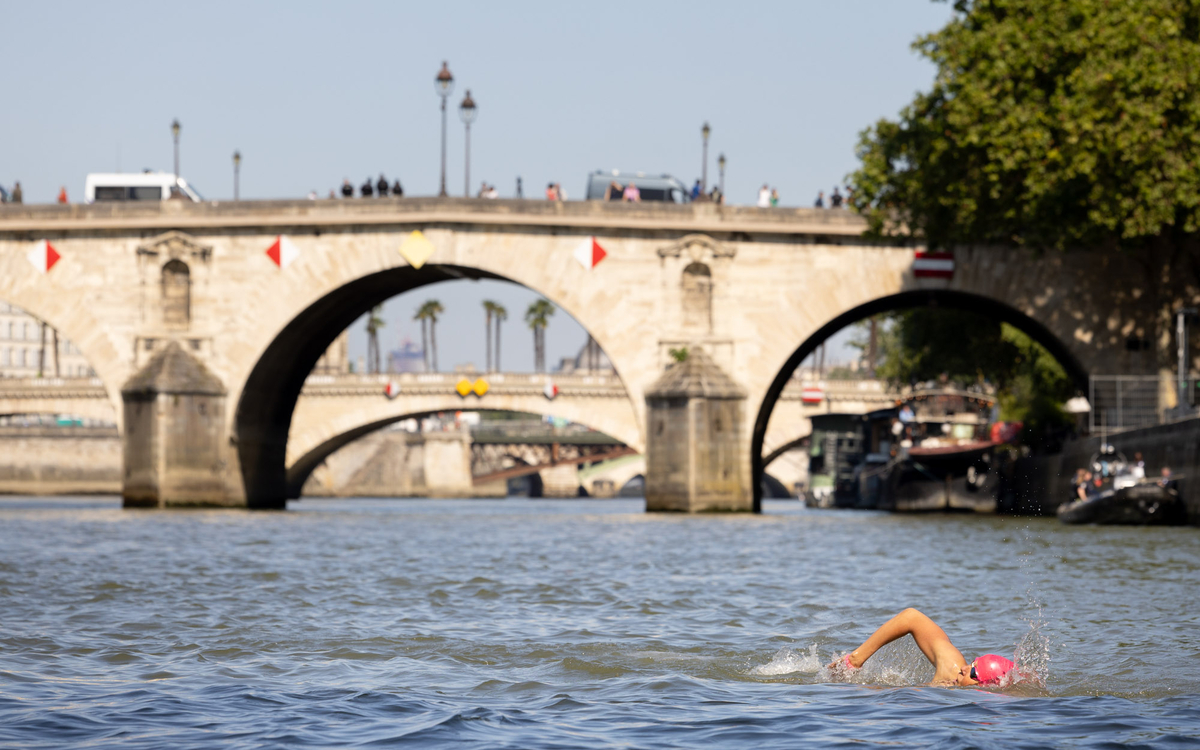 Un nageur pratiquant le crawl avec un bonnet rose dans la Seine.